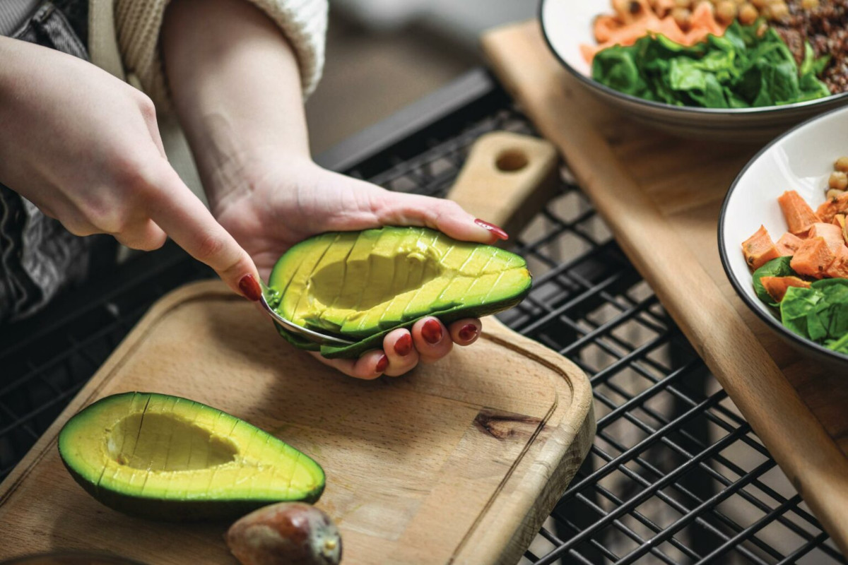 Close up photo of a person preparing an avocado for dinner