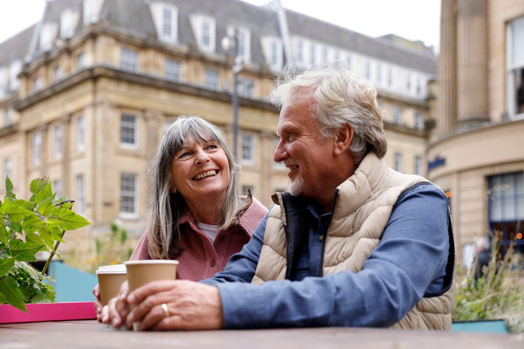An older man and woman drinking coffee outside