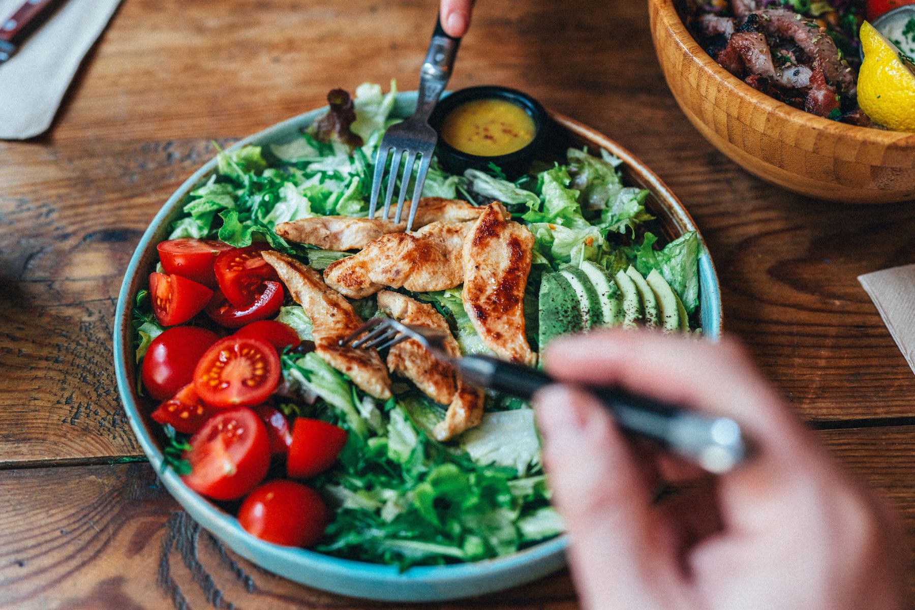 A fresh salad with chicken, avocado, tomatoes, lettuce and a dressing