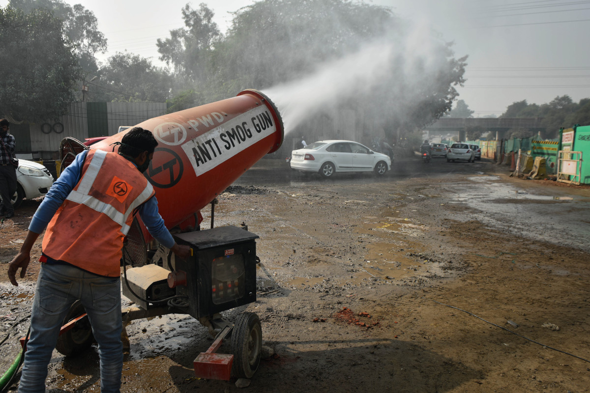 A worker uses an anti smog gun to reduce air pollution