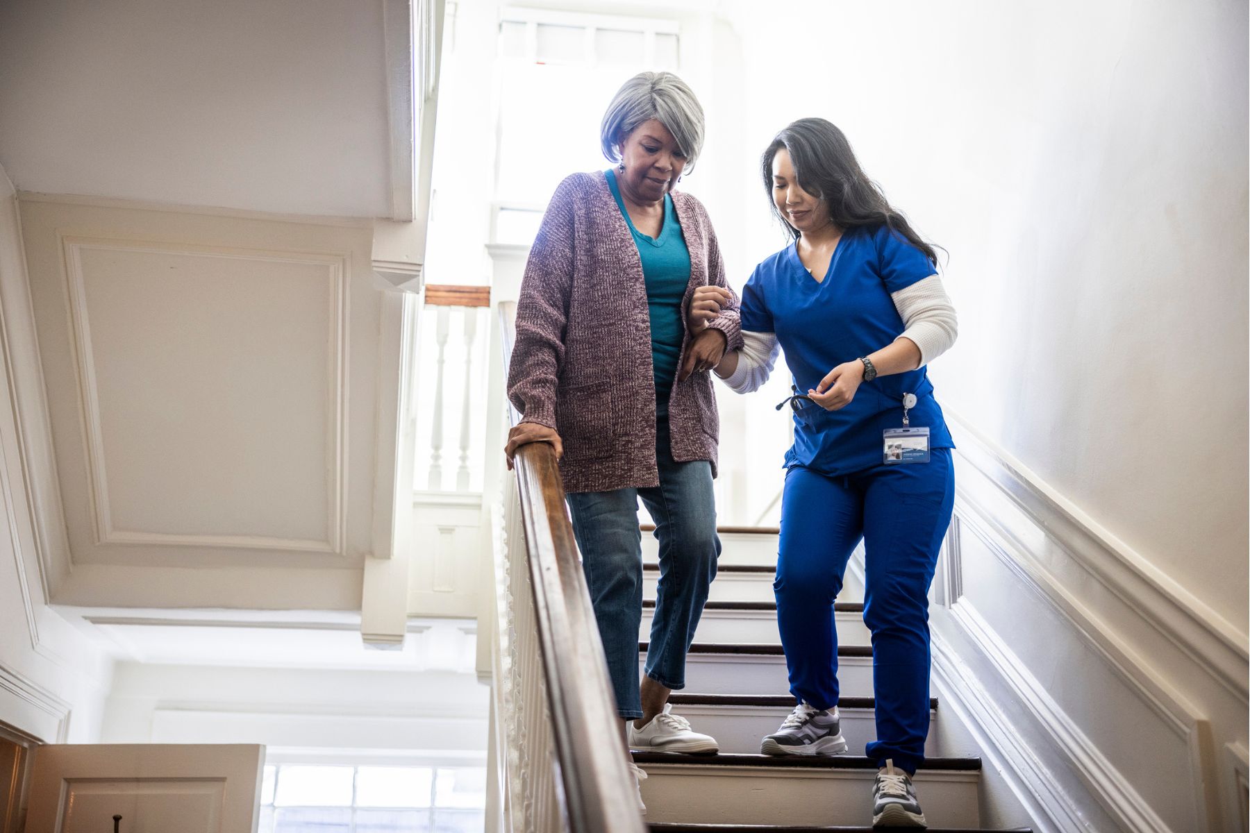 A woman is being helped down a flight of stairs by a nurse