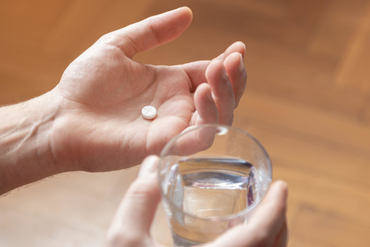 Hands holding medicine and a glass of water