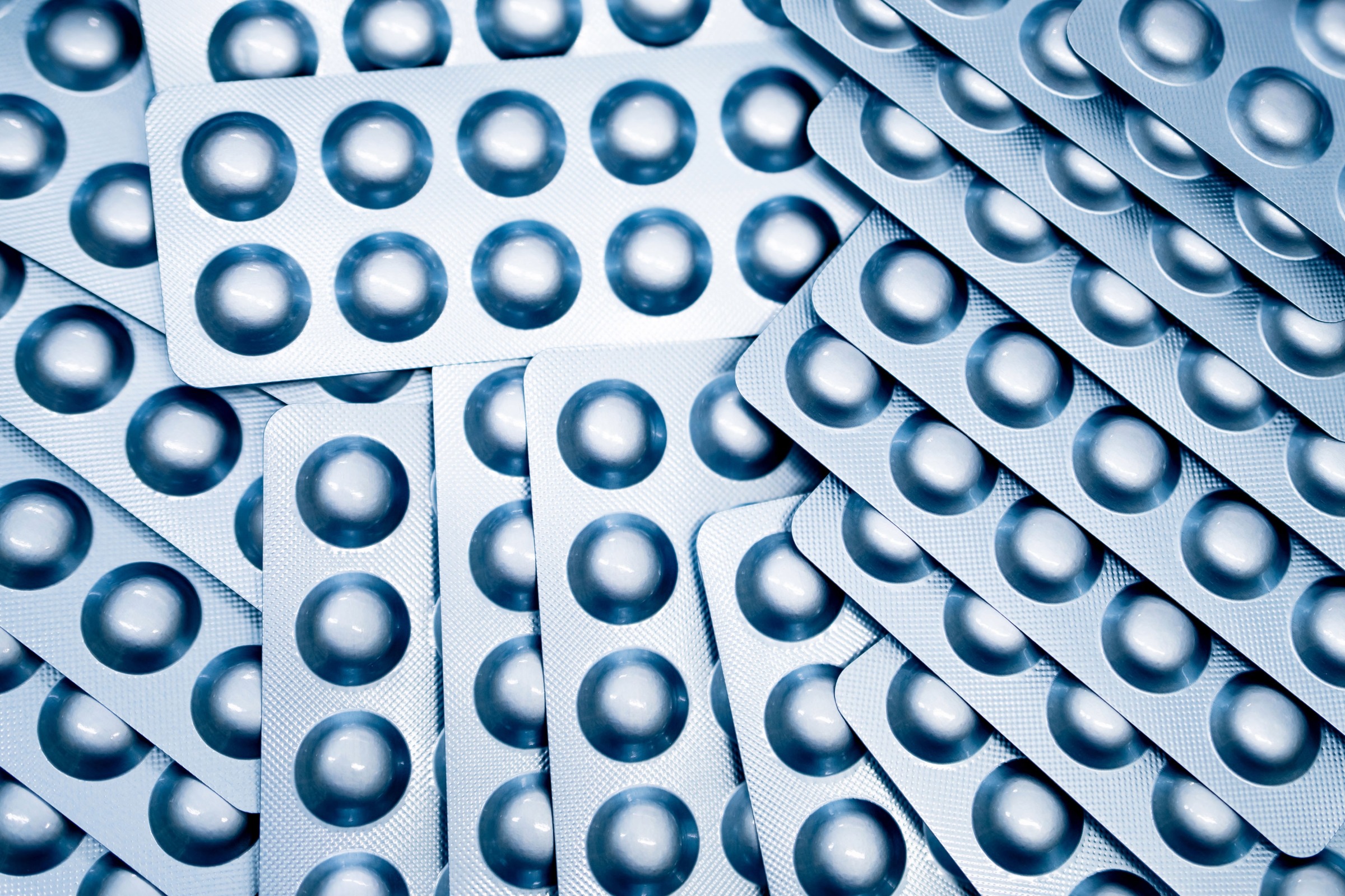 A stack of pill packets, known as blister packs, layered on top of each other.