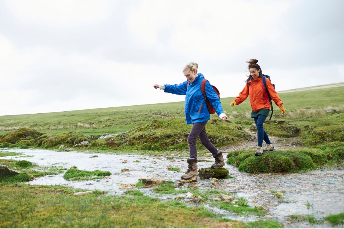 Two women hiking through a stream