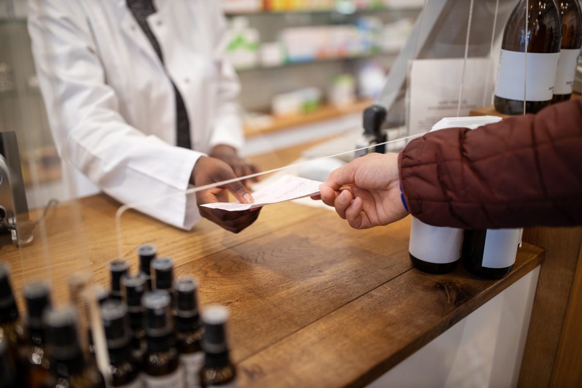 Cropped shot of a chemist giving prescription to a customer in a pharmacy
