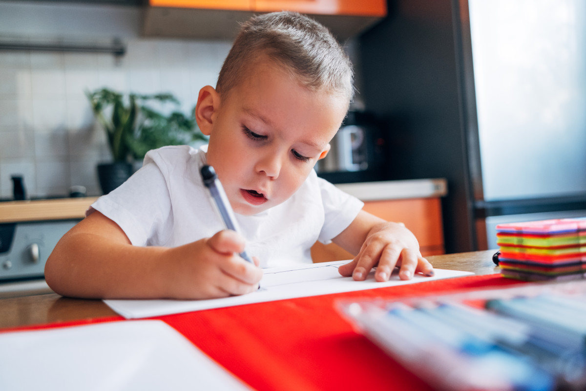 4 year-old draws with felt-tip pens while sitting at home at the table