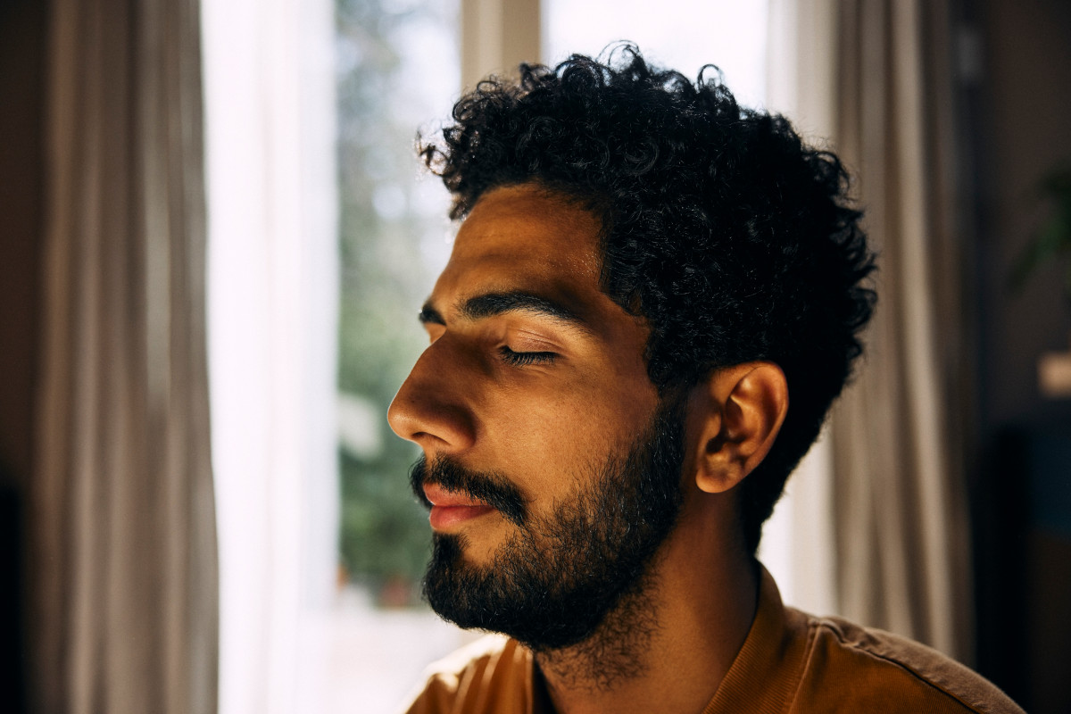 Close-up of man meditating with eyes closed at home
