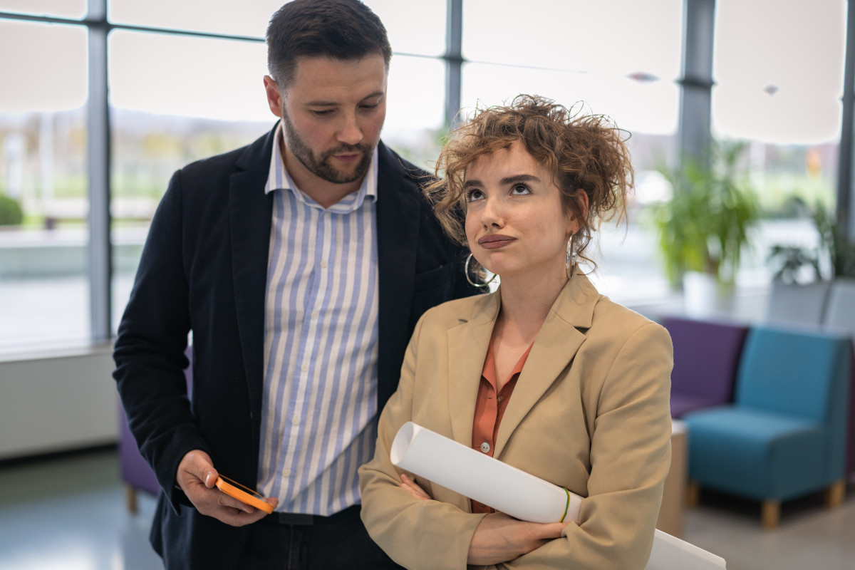 Female coworker looking annoyed while male colleague explaining something