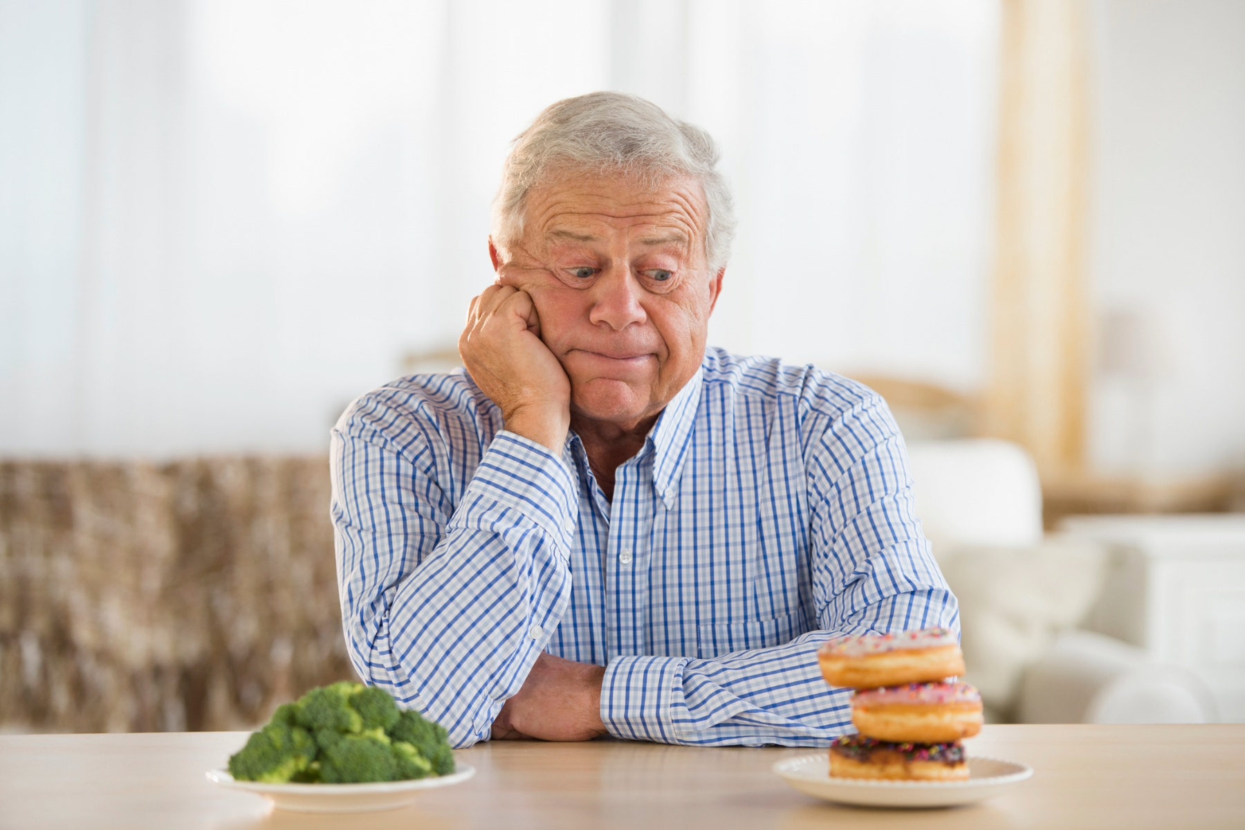 Senior man looking at a doughnut