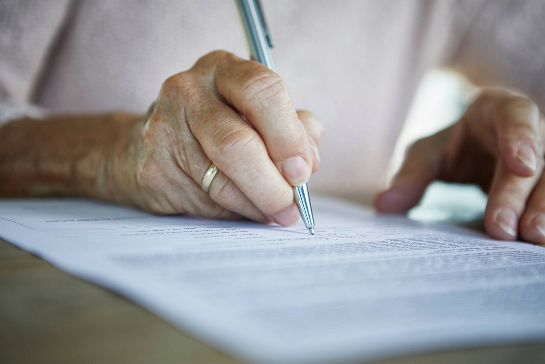 Hands of a mature person writing on paper
