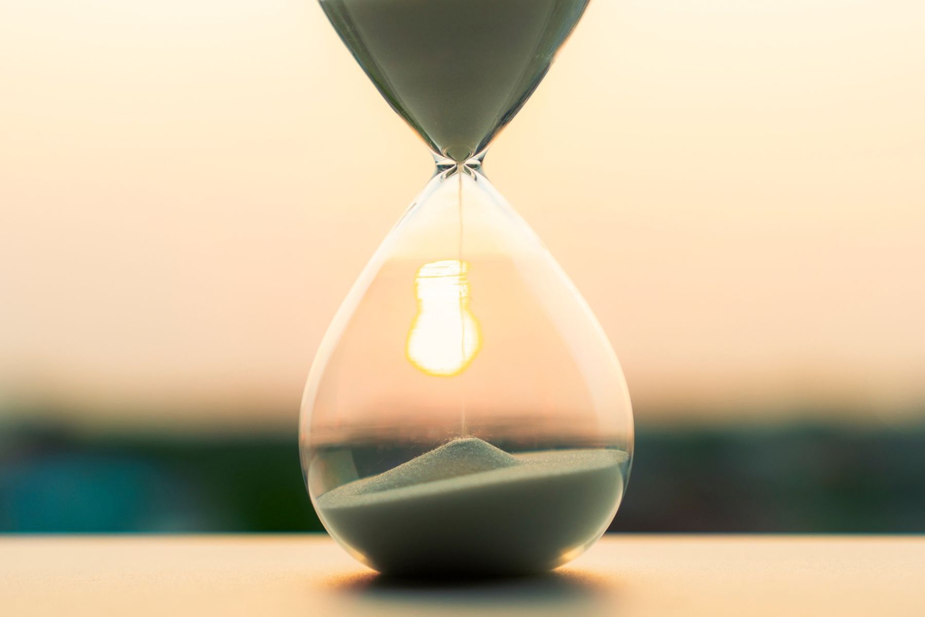 A glass sand timer with a sunset in the background