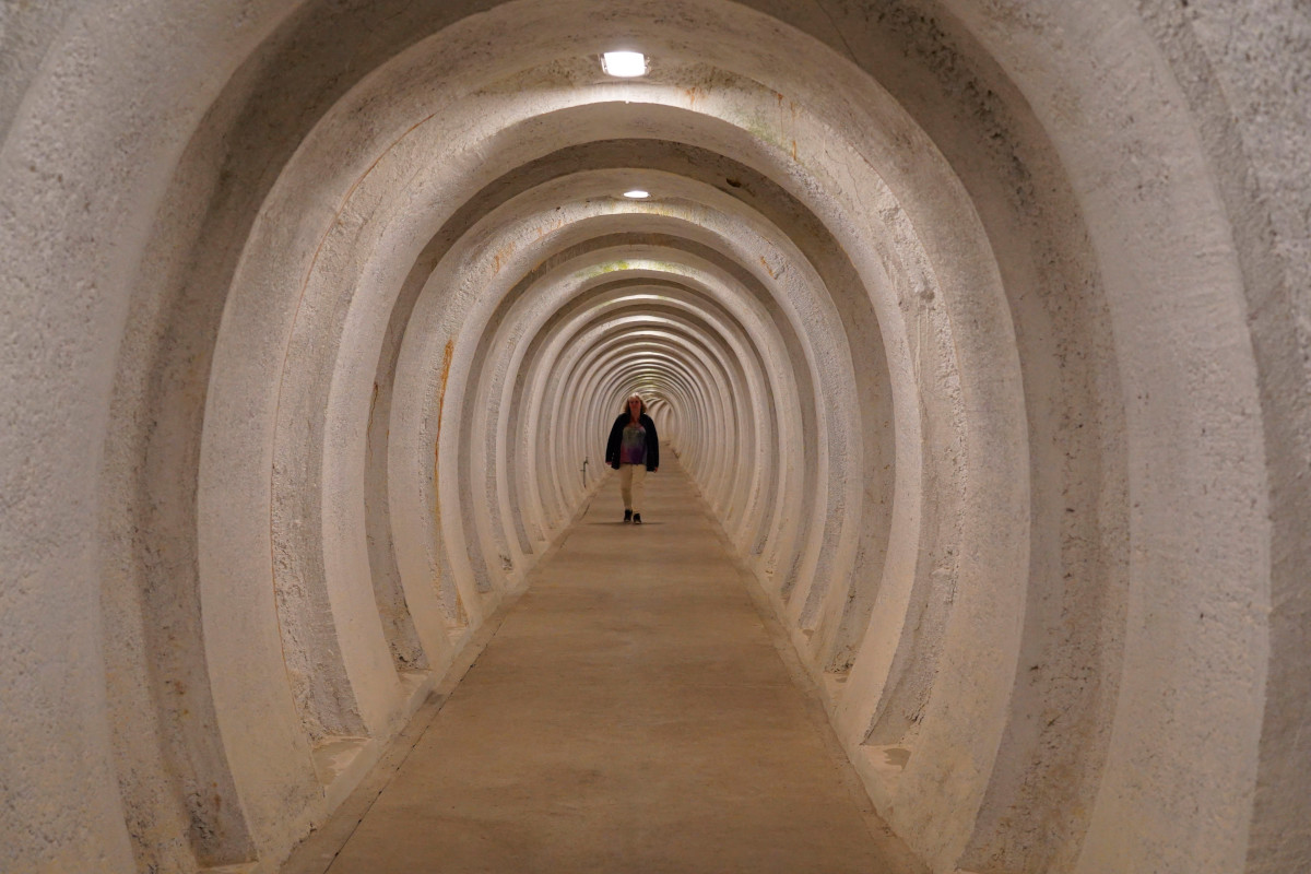 A person walking through a ultra-thick concrete tunnel