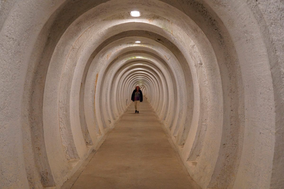 A person walking through a ultra-thick concrete tunnel