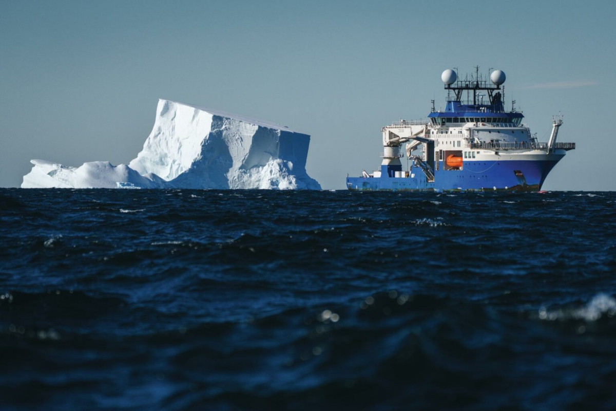 The Schmidt Ocean Institute research vessel Falkor (too) beside a huge block of ice in Antarctica