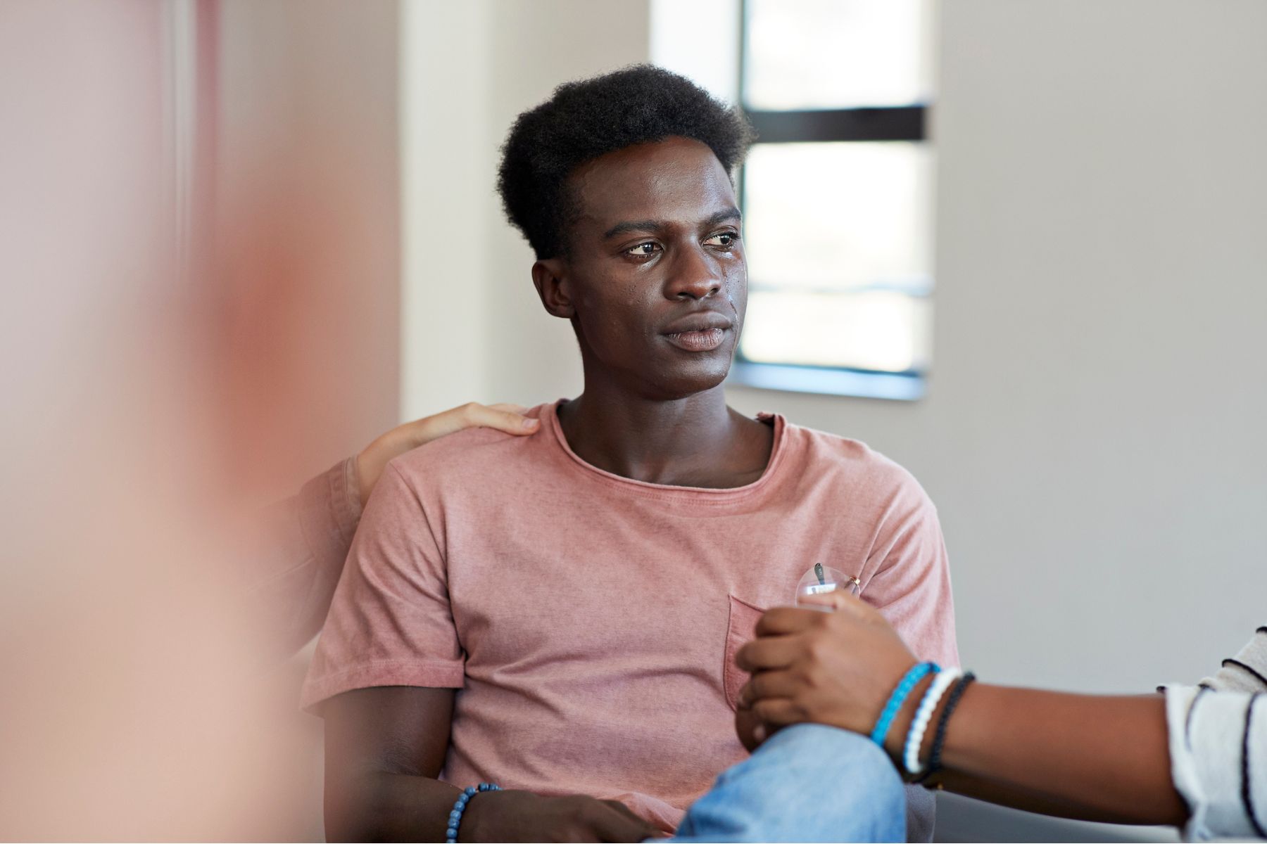 A young man cries and is consoled by friends
