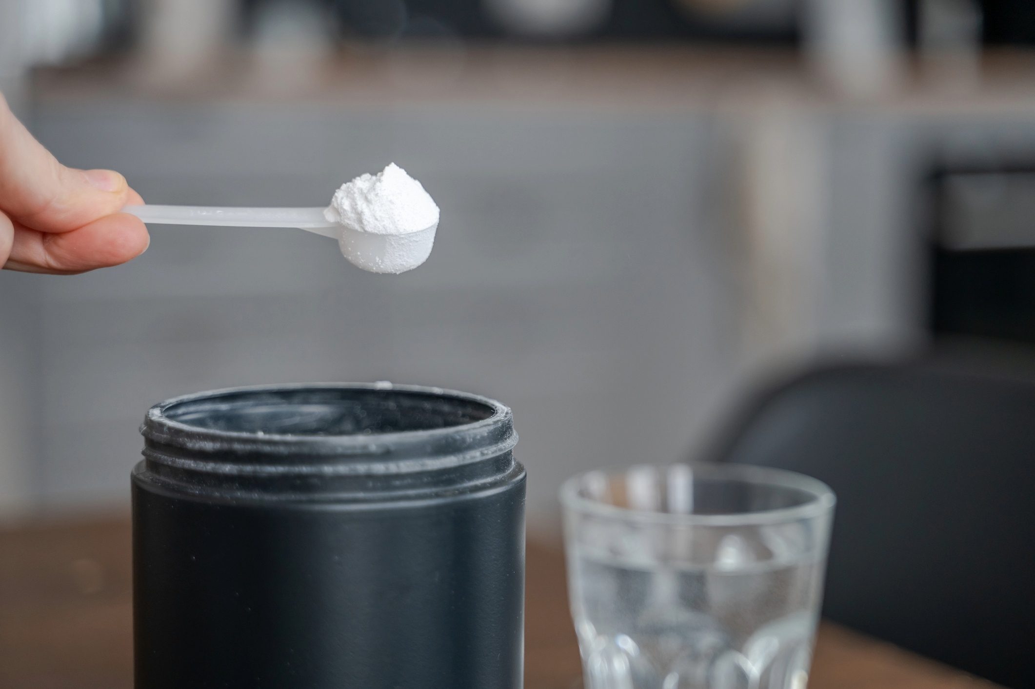 Person scooping creatine in glass of water.