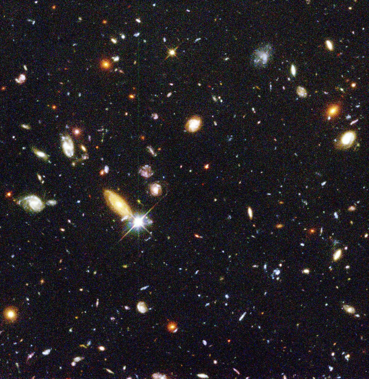 Hubble image showing thousands of distant galaxies, appearing as small dots and smudges in many colours, filling a tiny patch of deep space.