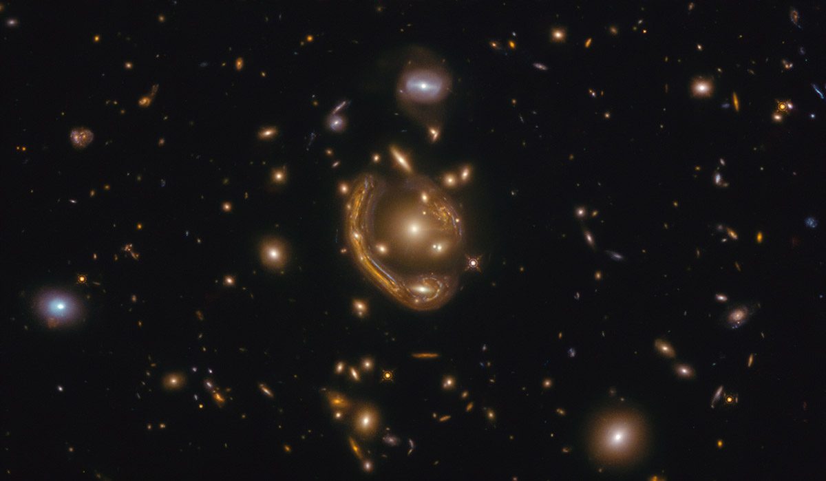 A Hubble image of space littered with stars with a seemingly glowing, metallic appearing orb in the centre.