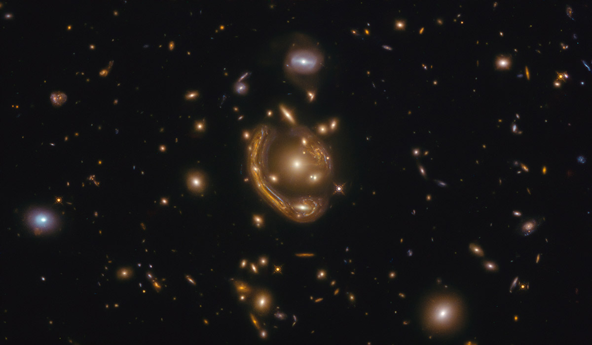 A Hubble image of space littered with stars with a seemingly glowing, metallic appearing orb in the centre.
