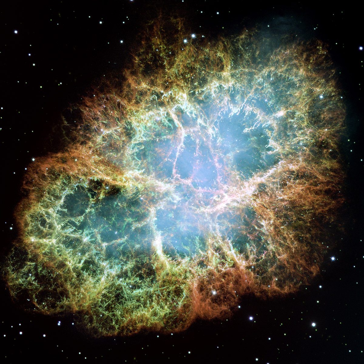 A Hubble image of a nebula with a web of red and blue filaments expanding from a bright central region, surrounded by scattered stars.