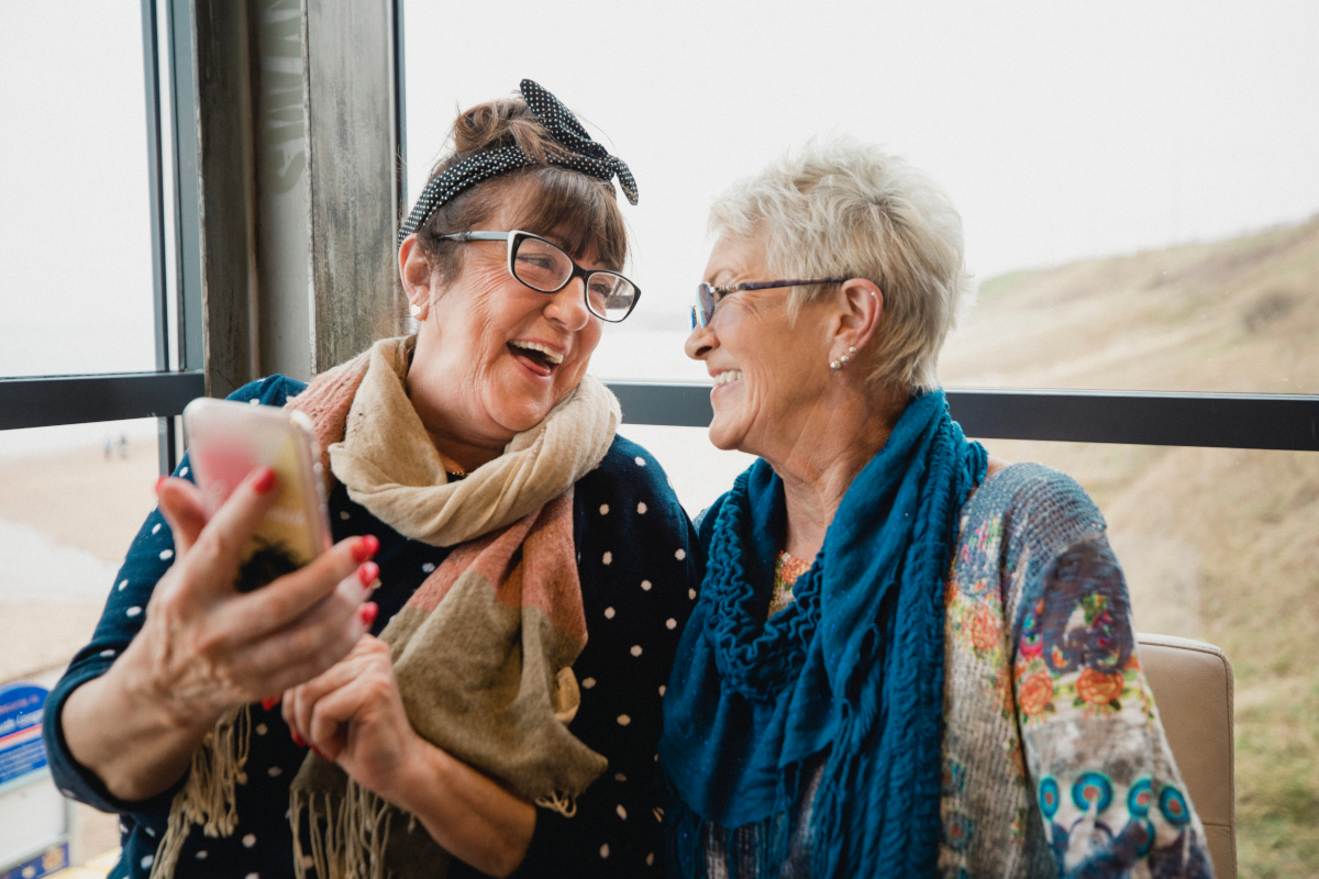 Two old friends laughing at a smartphone screen.