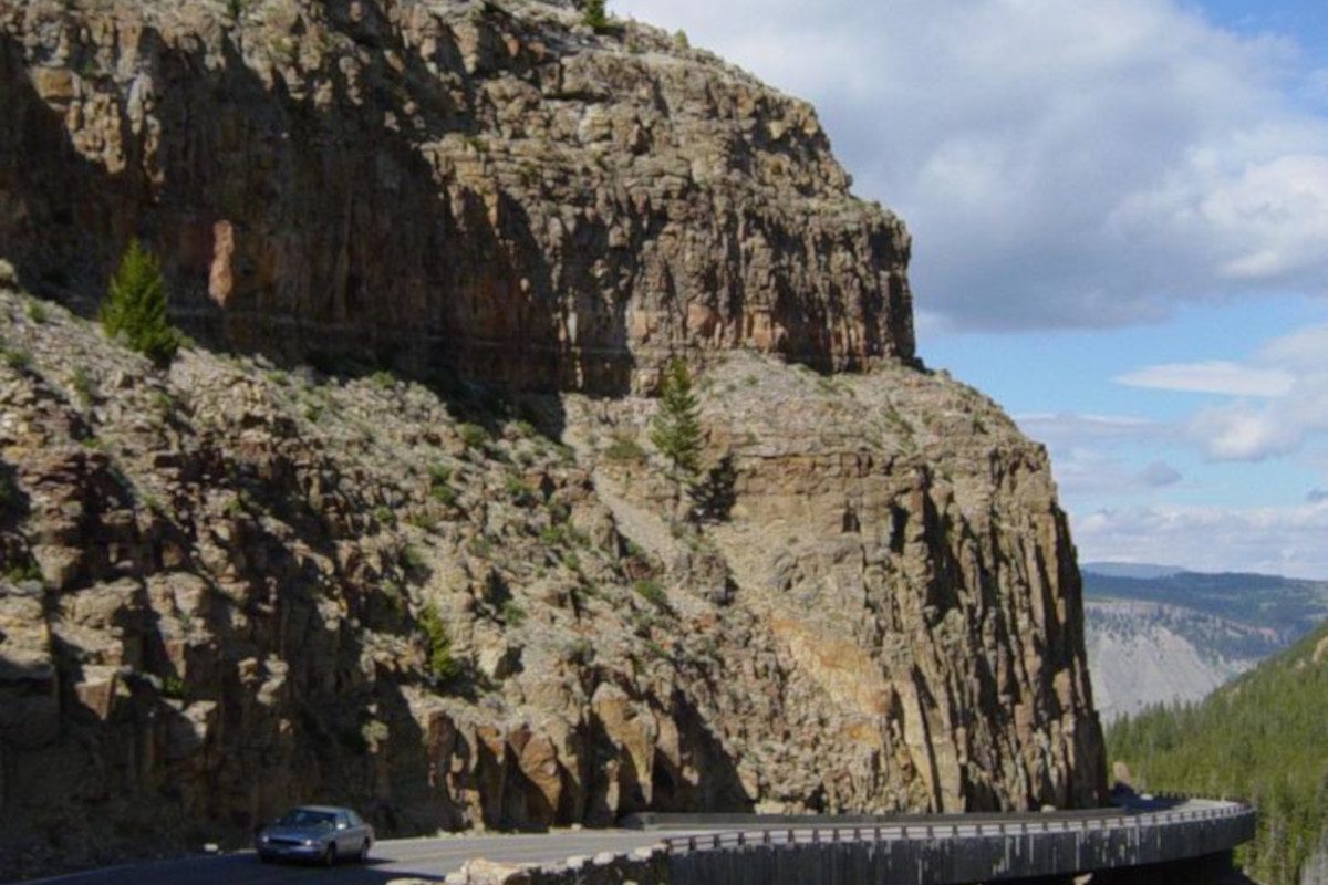 A car driving on a road along a rocky mountain at Huckleberry Ridge