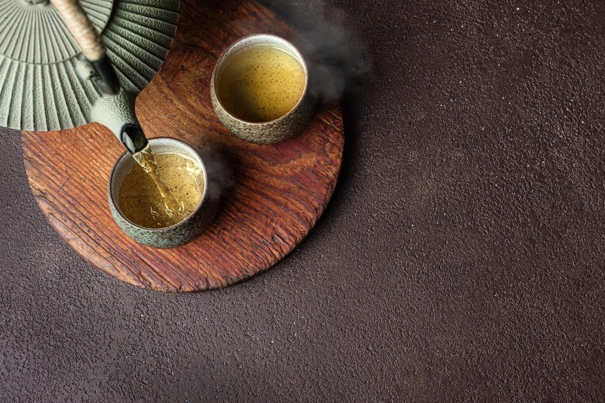 Pouring steaming green tea into cups