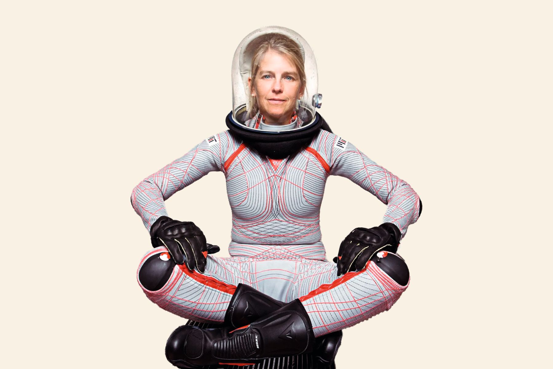 Photo of a person sat cross-legged in the BioSuit, a futuristic-looking spacesuit