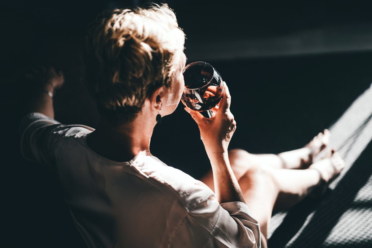 Over the shoulder shot of a person drinking a glass of wine