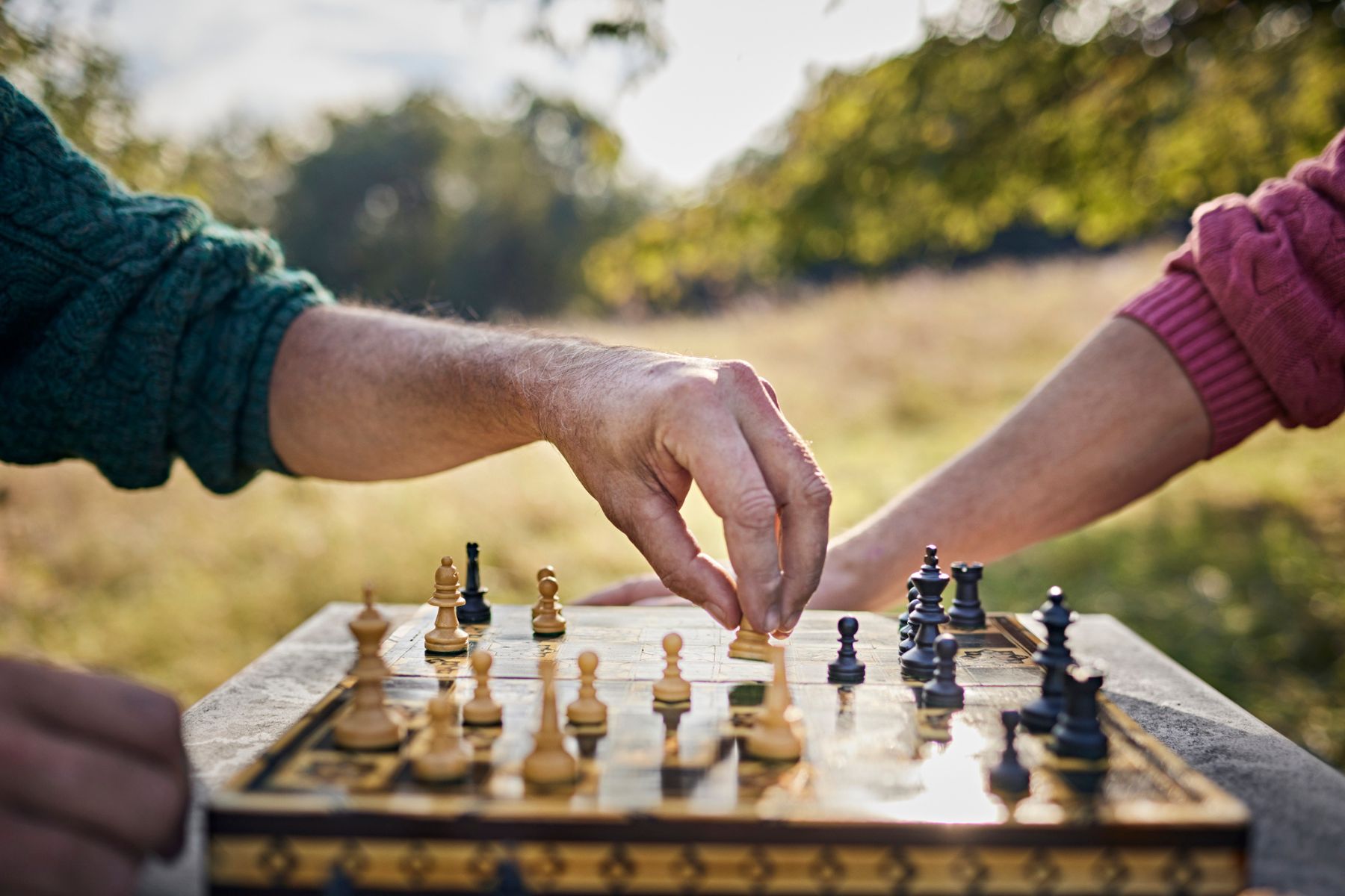 Two hands play chess outside