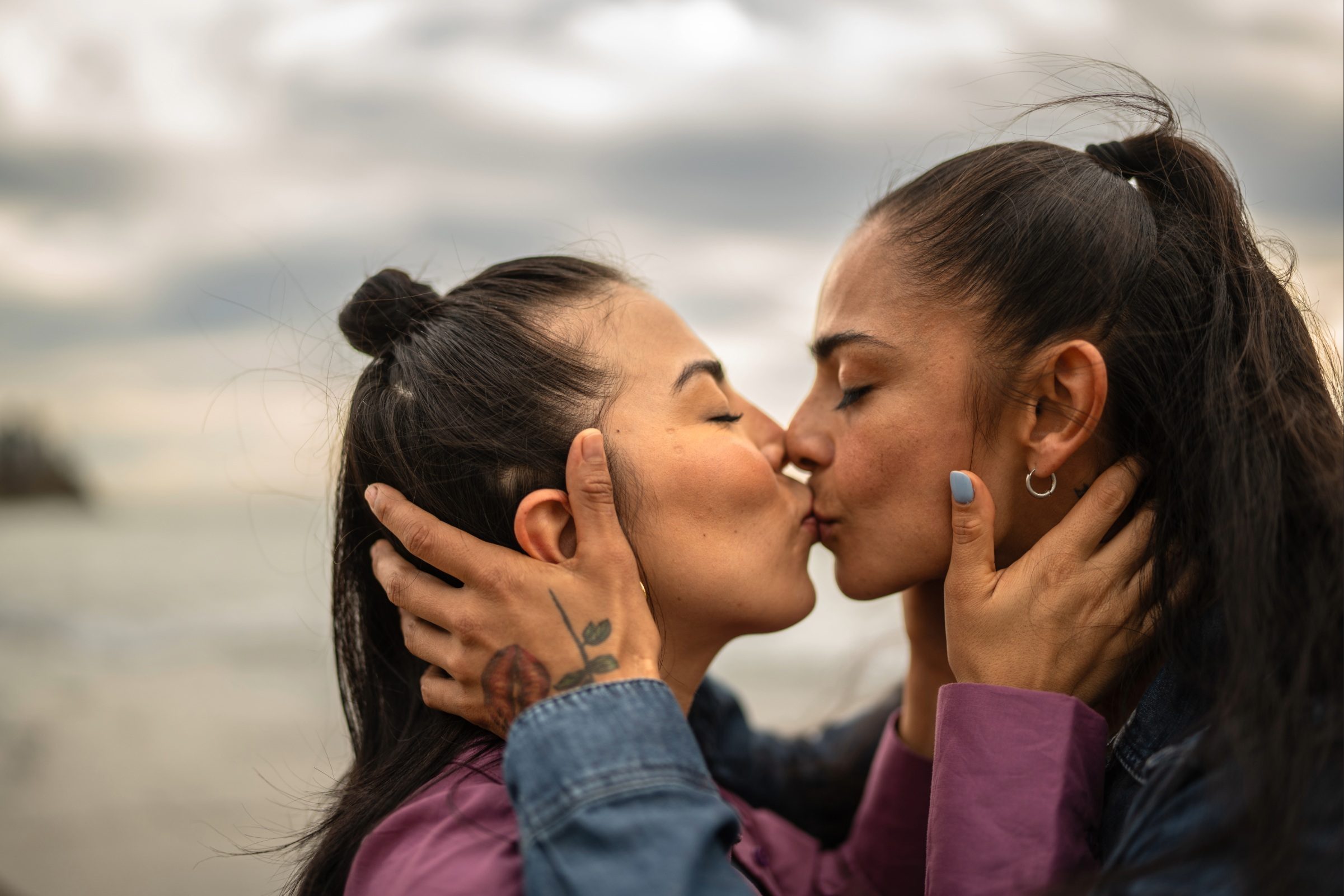 Two women kissing on a beach.