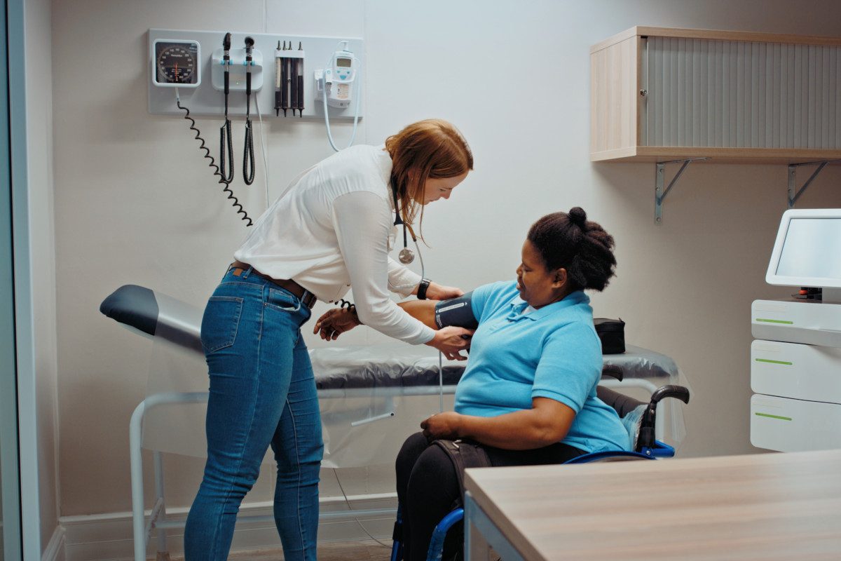 Doctor taking patient blood pressure in hospital consultation or examination room