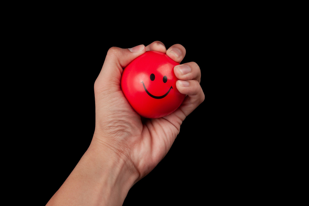 Hand squeezing a red stress ball isolated on black background