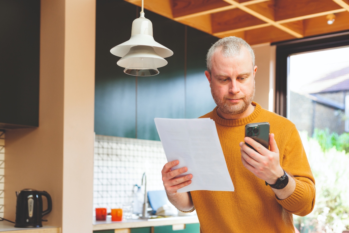 An adult man in his 30s checking his energy bills at home