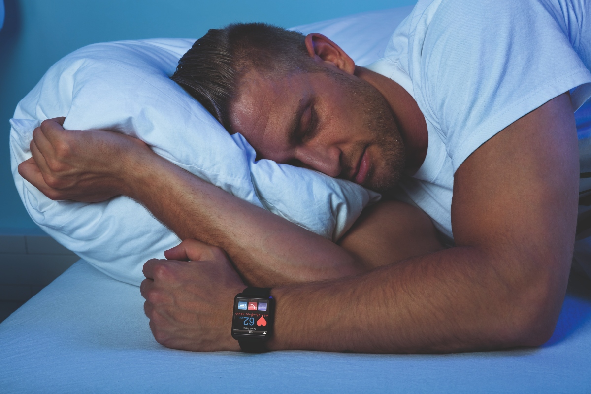 Man Sleeping With Smart Watch In His Hand Showing Heartbeat Rate