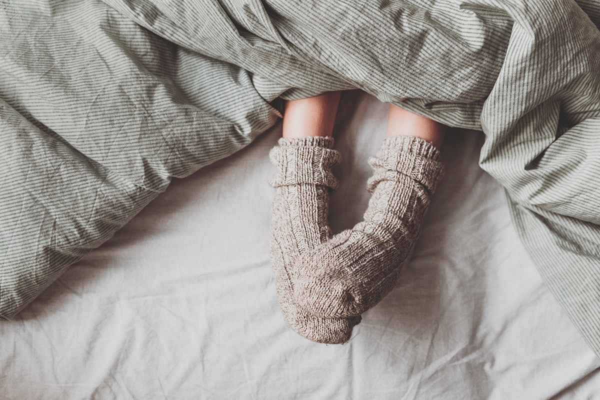 A medium shot of feet in socks under a blanket