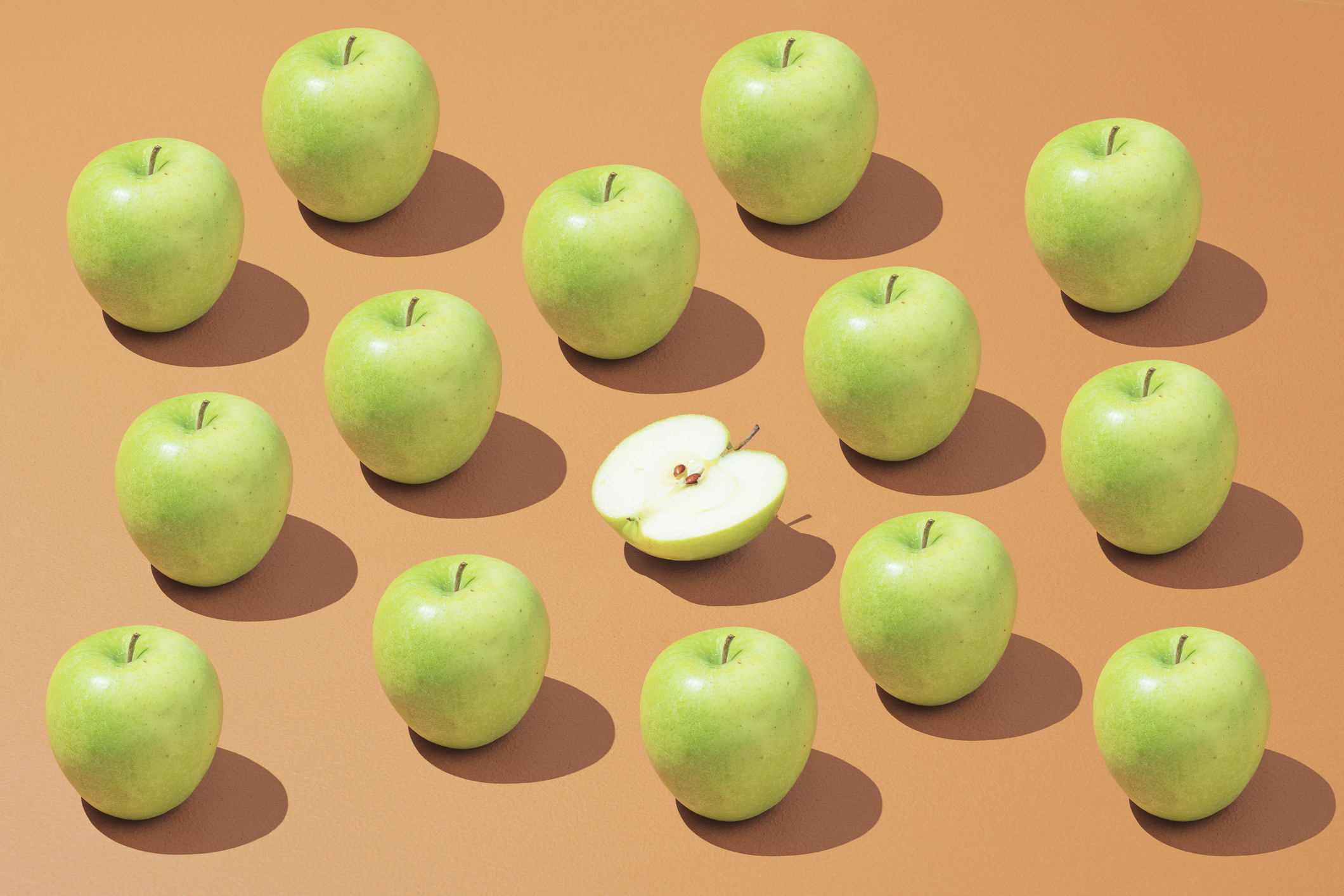 Collection of green apples on orange background.