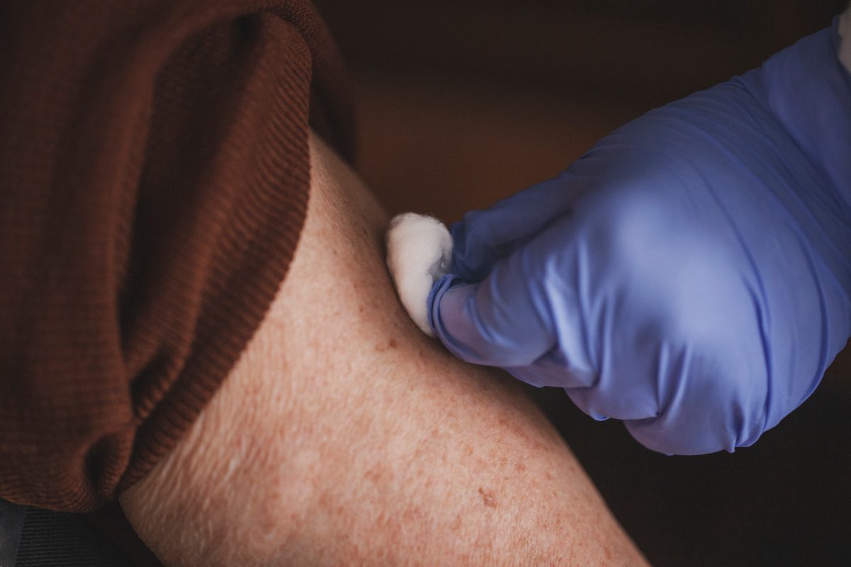 Nurse gives vaccine to senior person at home