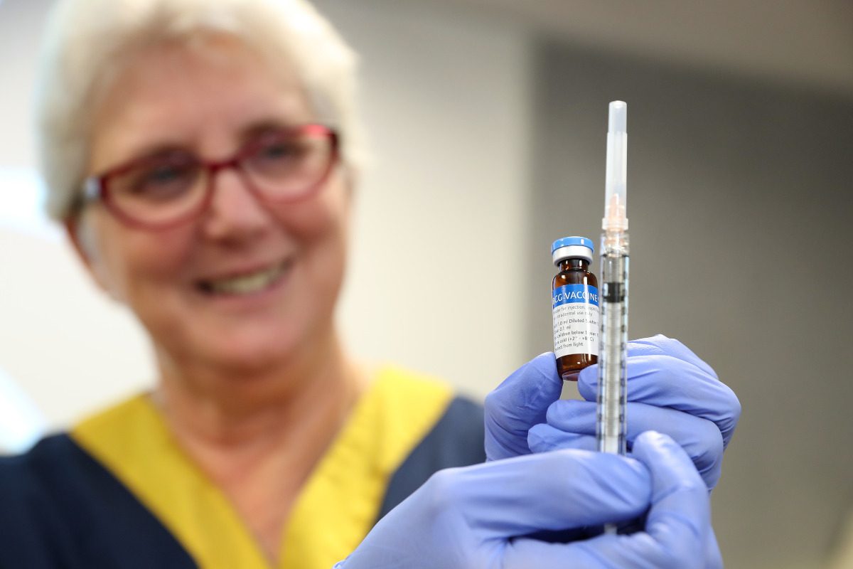 A clinical staff member holds a BCG vial and syringe