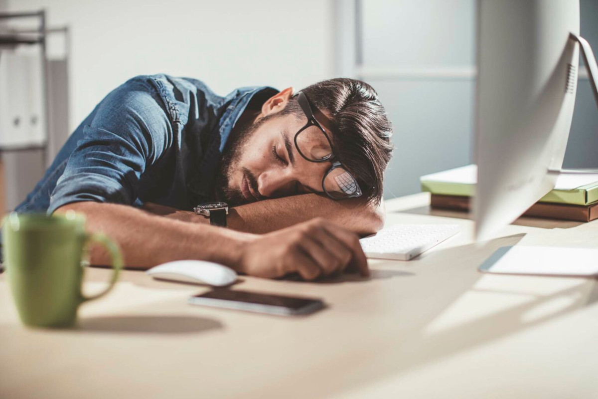 Photo of a person asleep at their work desk