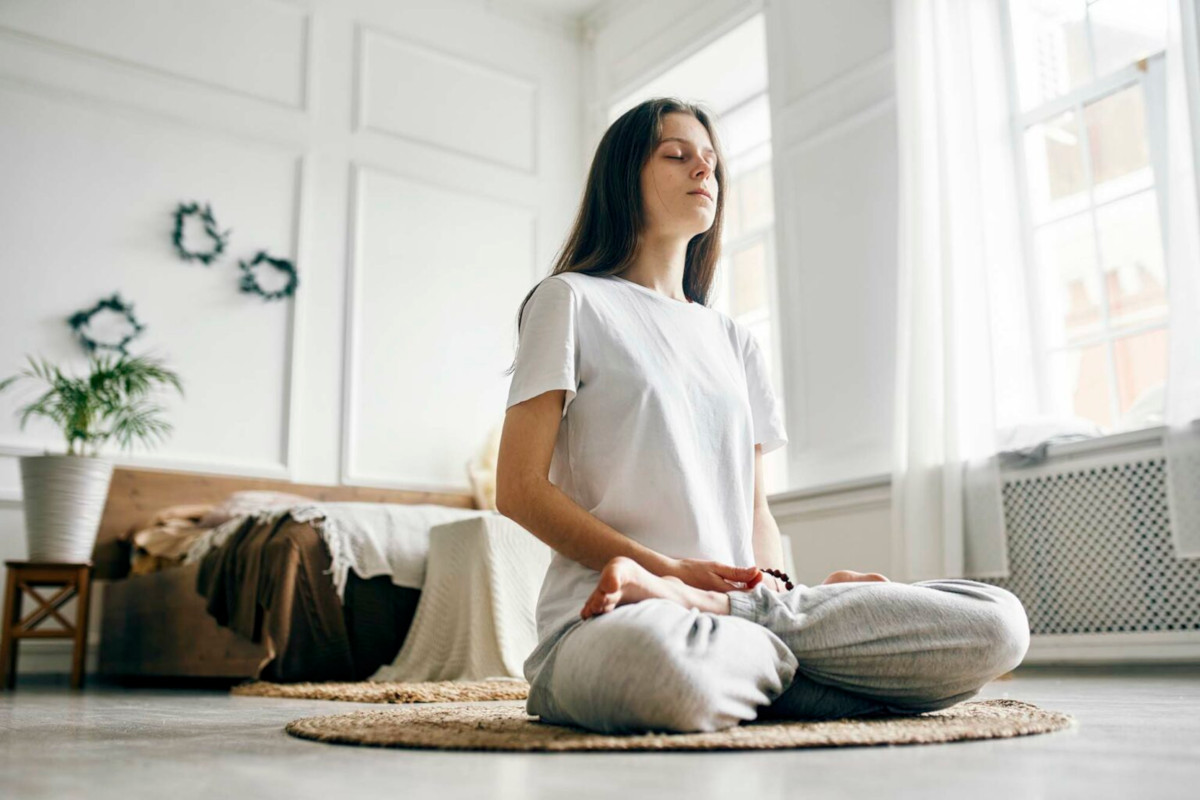 Photo of a person meditating on their bedroom floor