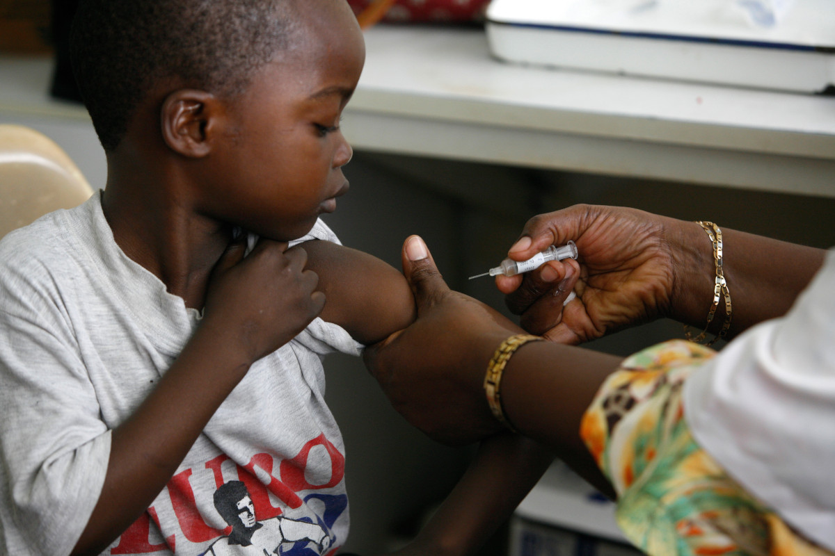 Photo of a young child receiving a vaccine. They are looking at the needle inquisitively