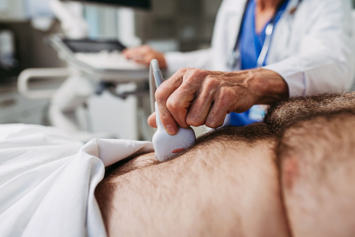 Doctor performing an ultrasound on male patient's abdomen