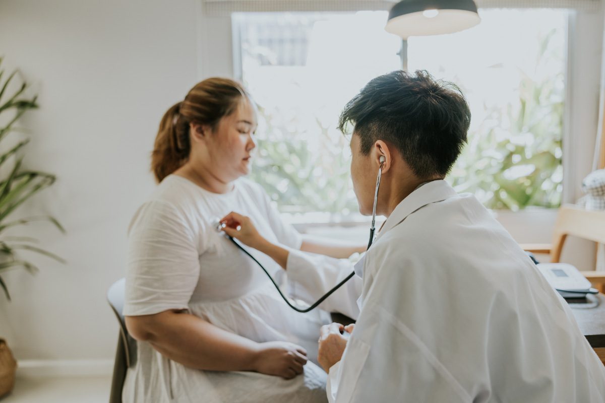 An overweight patient is checked on by a doctor