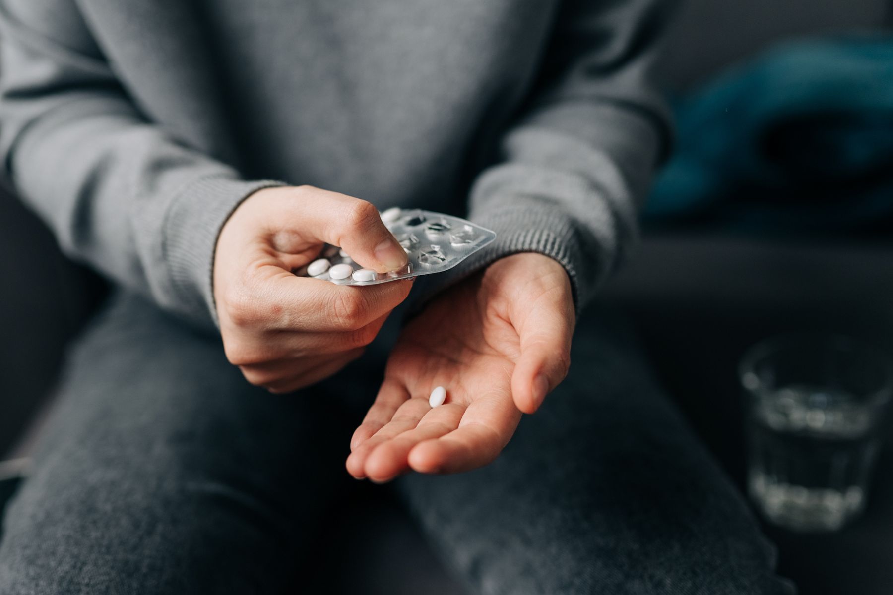 A person pops a pill out of a blister pack