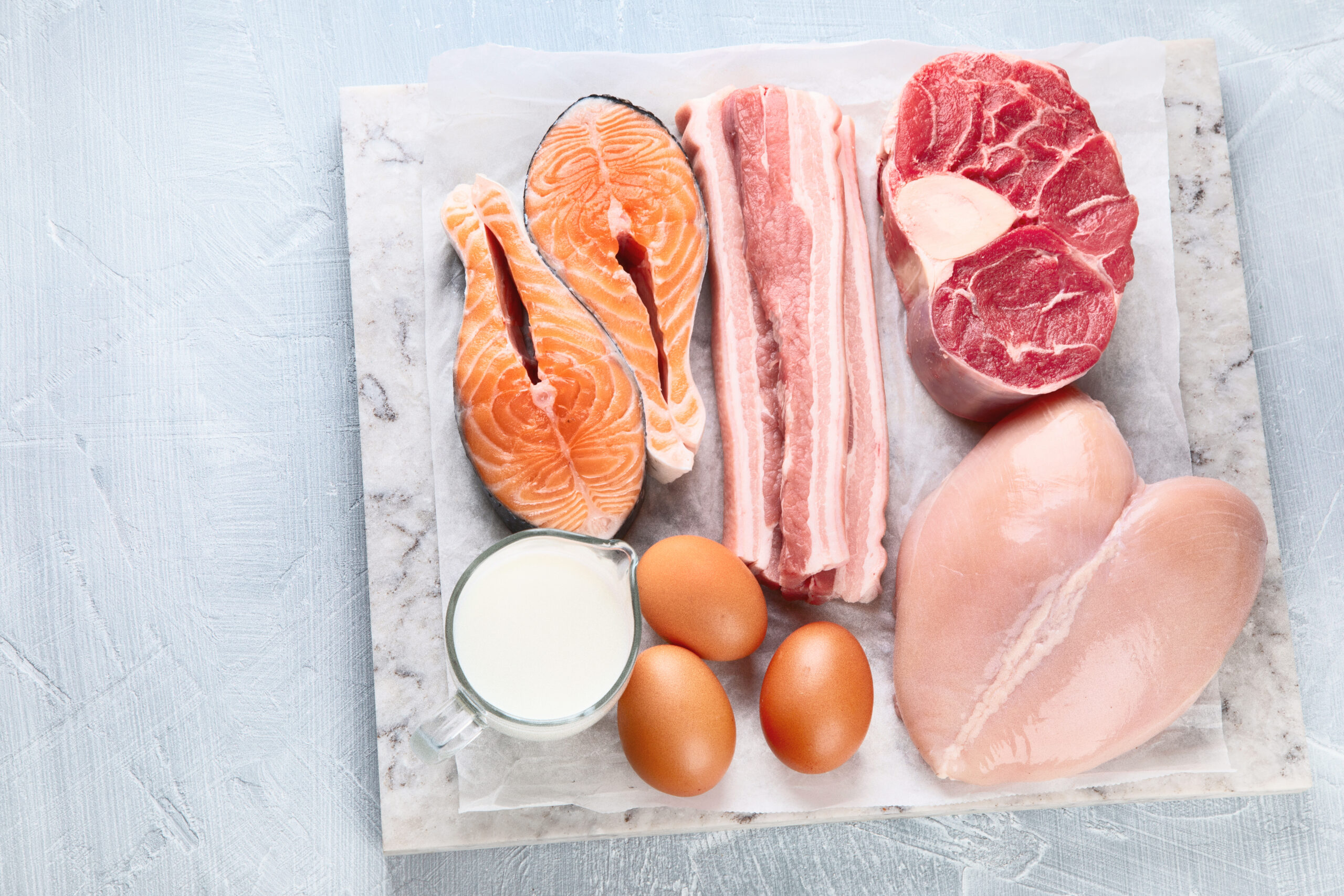 Eggs and raw meat on a marble chopping board.