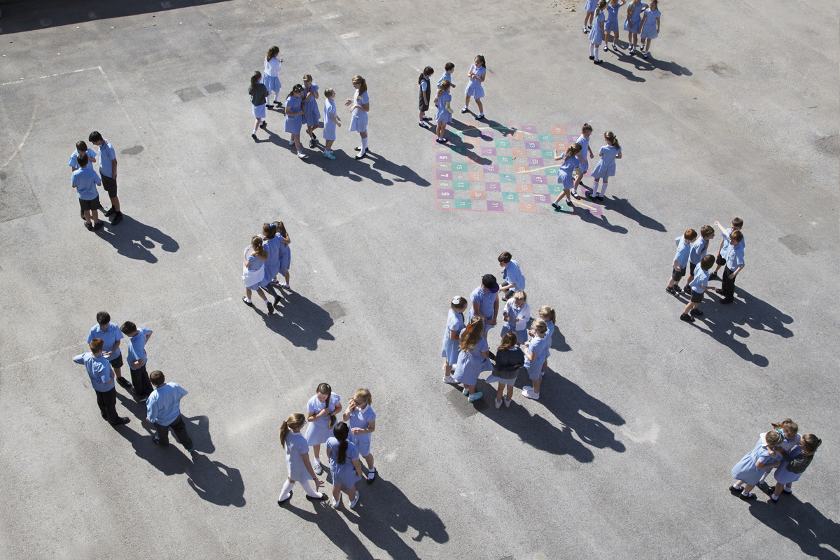 Aerial shot of children stood in groups on a playground.