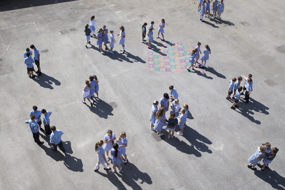 Aerial shot of children stood in groups on a playground.