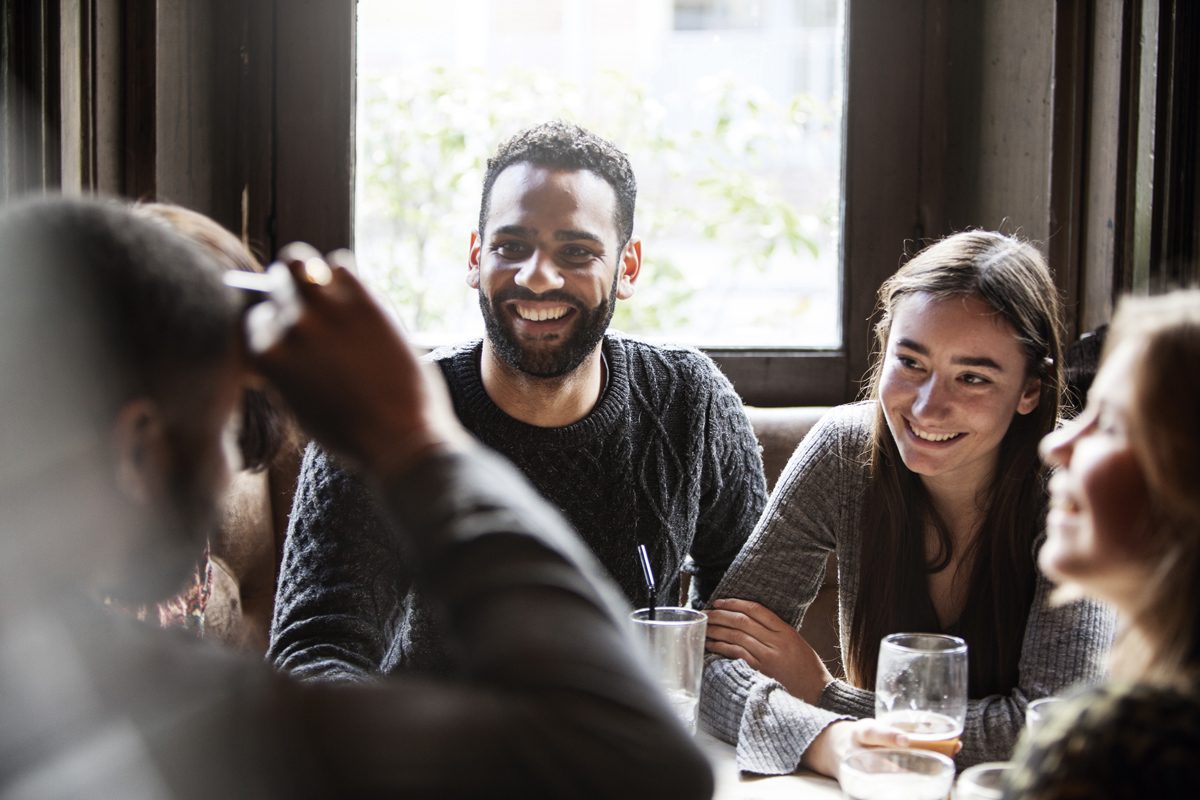 A group of people sat around the table at a pub smiling.
