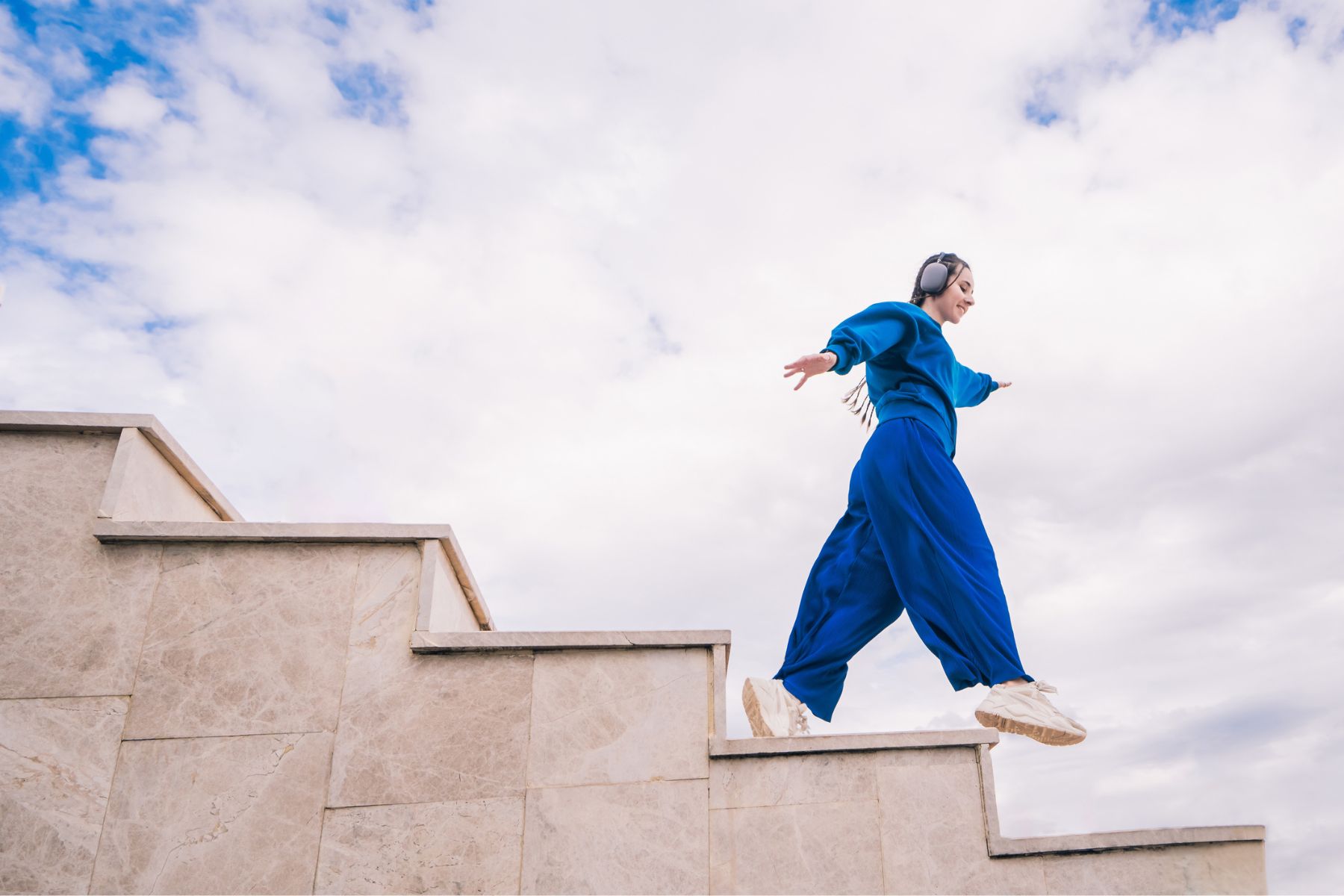A woman in a blue jumpsuit walking down stairs